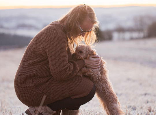 Life Coach mit Cavapoo bei einem Spaziergang im warmen Abendlicht